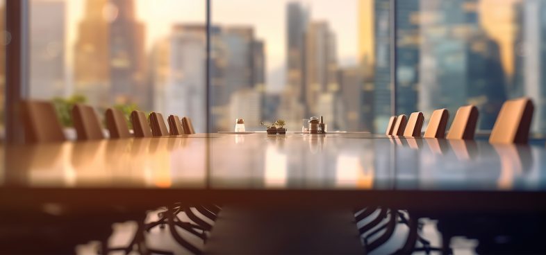 A board room against a backdrop of windows showing a cityscape.