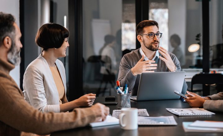 Pictorial representation of a group of individuals conversing in an office setting.