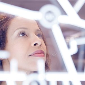 Pictorial representation of a woman analyzing a bright, white characters on a clear screen.