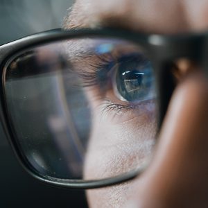 Pictorial representation of Iran cyber attacks. Close-up of a person wearing glasses, with computer code reflected in the lenses.