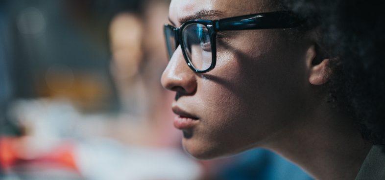 Pictorial representation of a severe Linux vulnerability. Close-up of a woman wearing glasses and focusing intently on a computer screen.