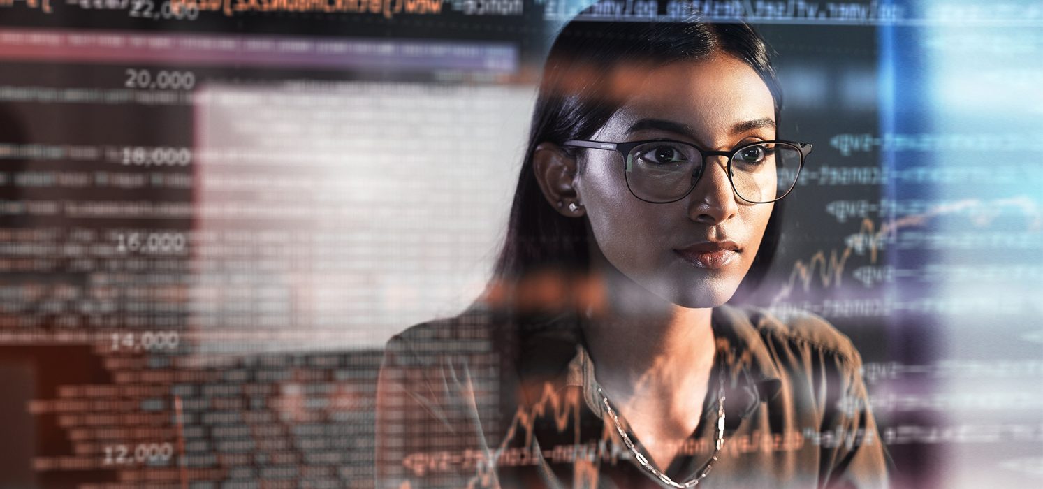 Pictorial representation of a woman in glasses viewing a reflection of a monitor screen. The reflection features multicolored numbers, arrows, and graphs.